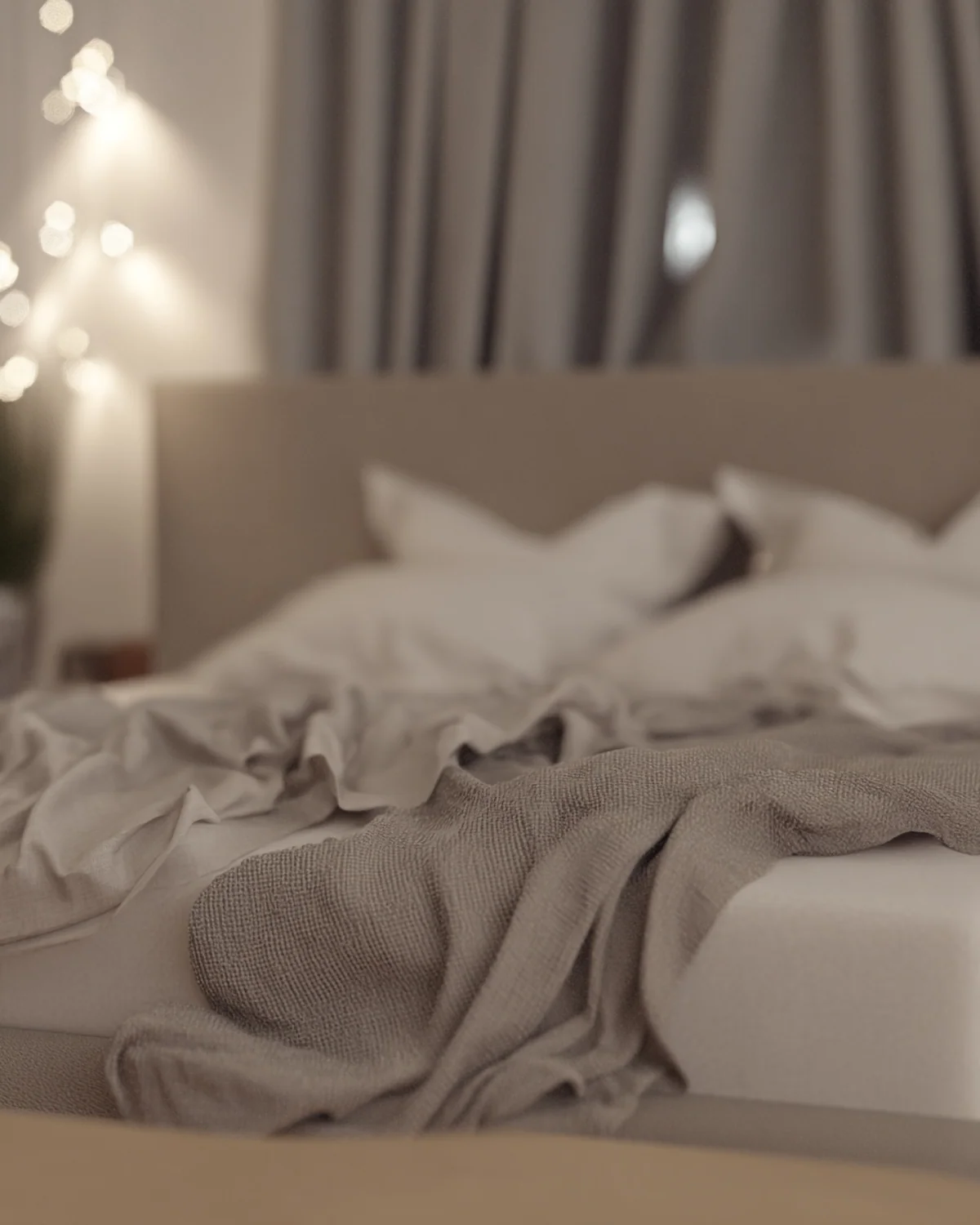 Softly focused neutral bedroom with layered linen and evening lights.
