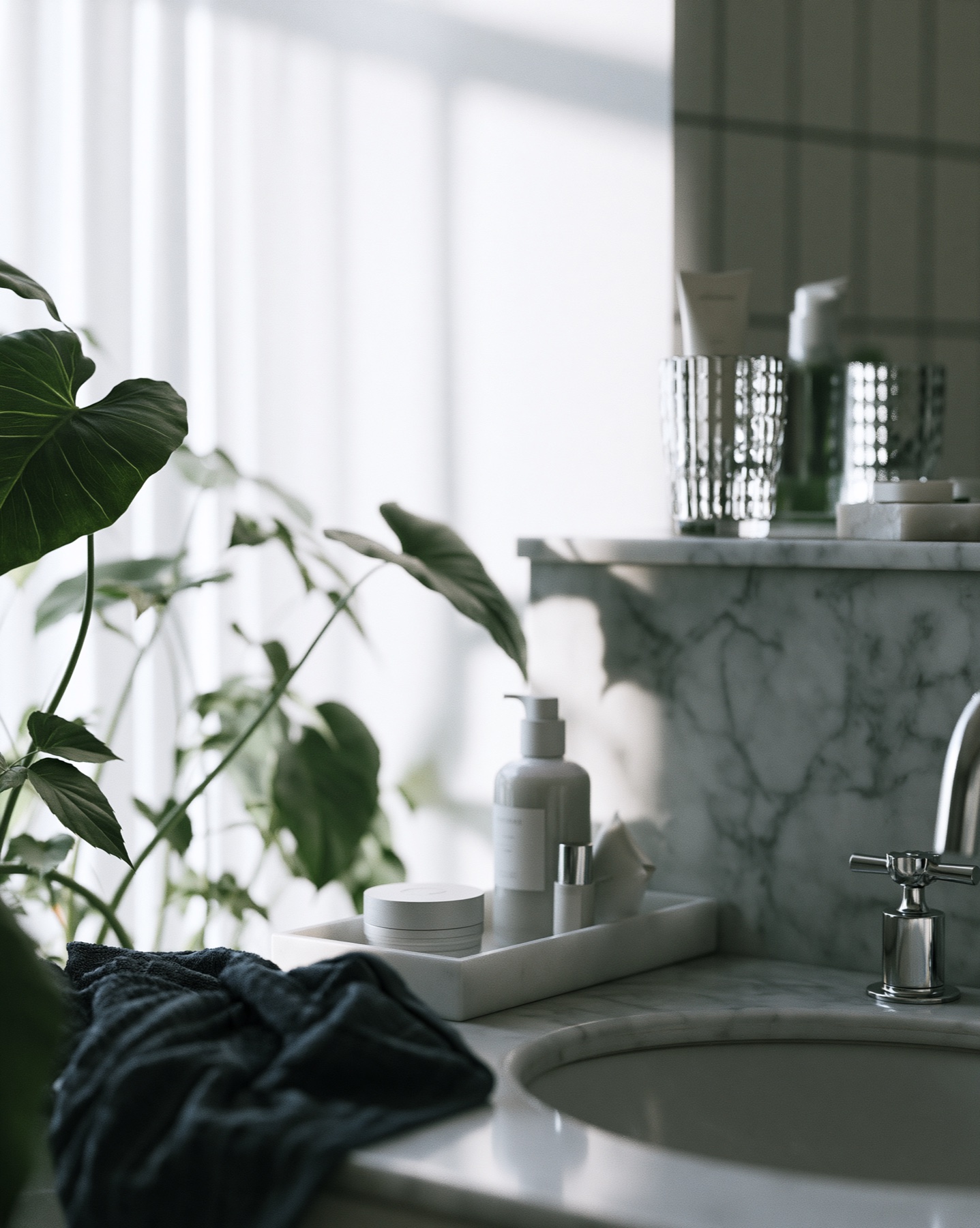 Skincare collection beside a marble basin in cool botanical light.