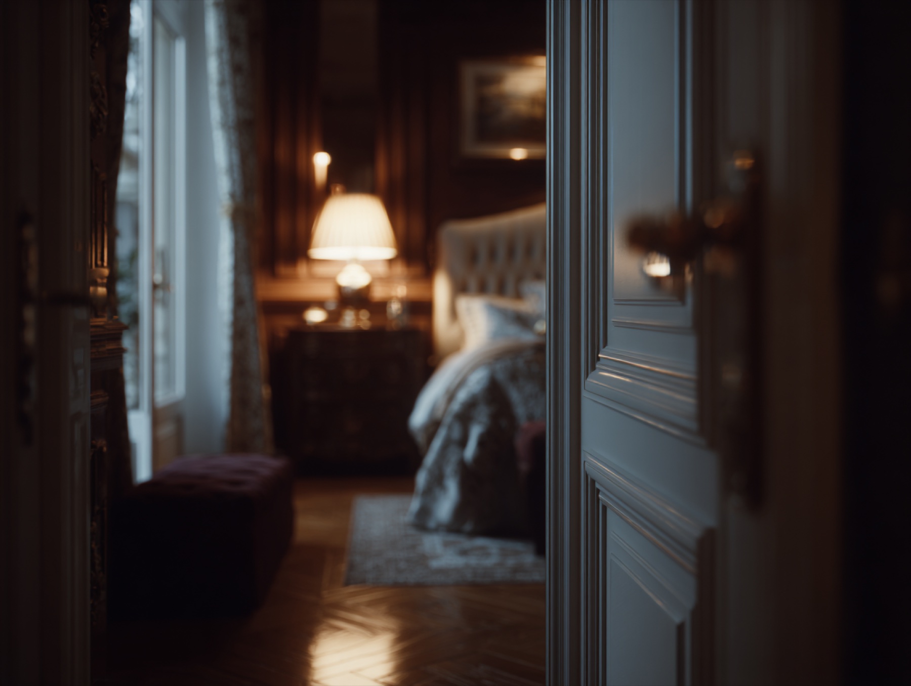 Dark luxury bedroom seen through a doorway in cinematic evening light.