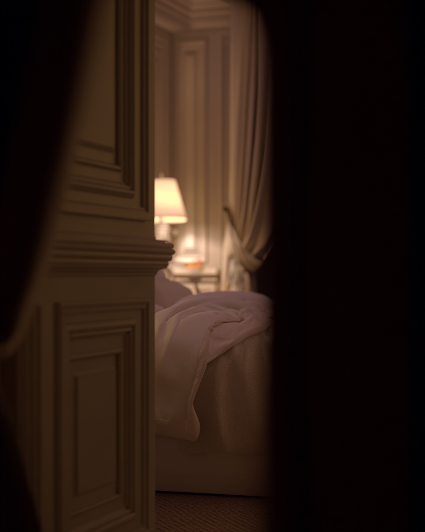 Luxury bedroom glimpsed through a partially open doorway at night.