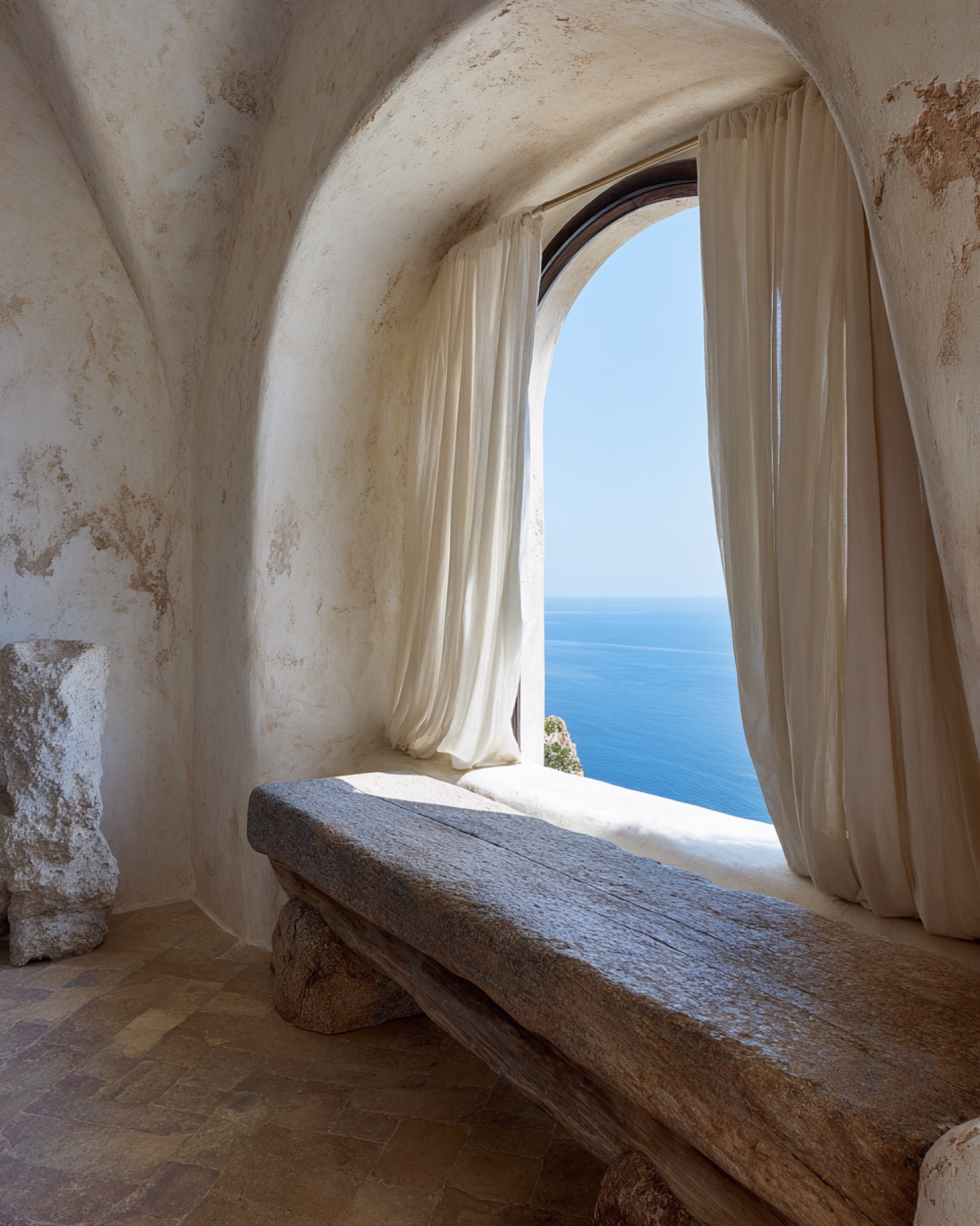 Mediterranean stone room opening onto a calm blue sea.